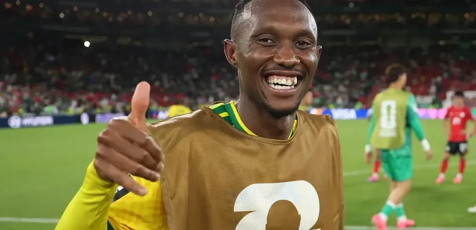 Futbolchi maydonda tabassum qilib qo'lini ko'taradi