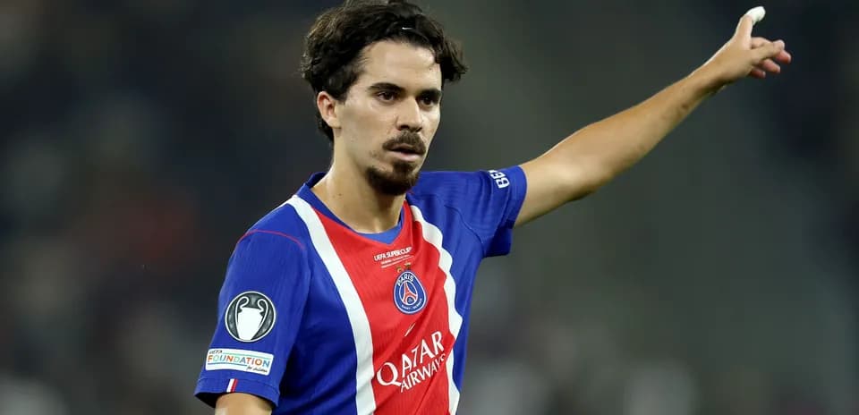 Futbolchi maydonda qo'lini ko'tarib turibdi