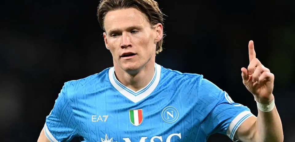 Futbolchi Napoli formasida, bir qo'lni ko'tarib turibdi