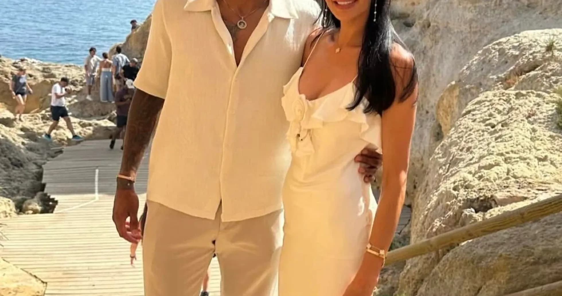 Couple posing near rocky seaside during sunny day