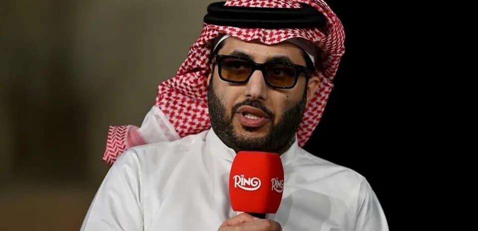 Shirted man speaking into a microphone during event