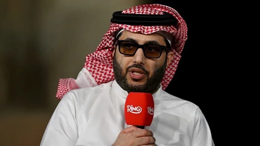 Shirted man speaking into a microphone during event