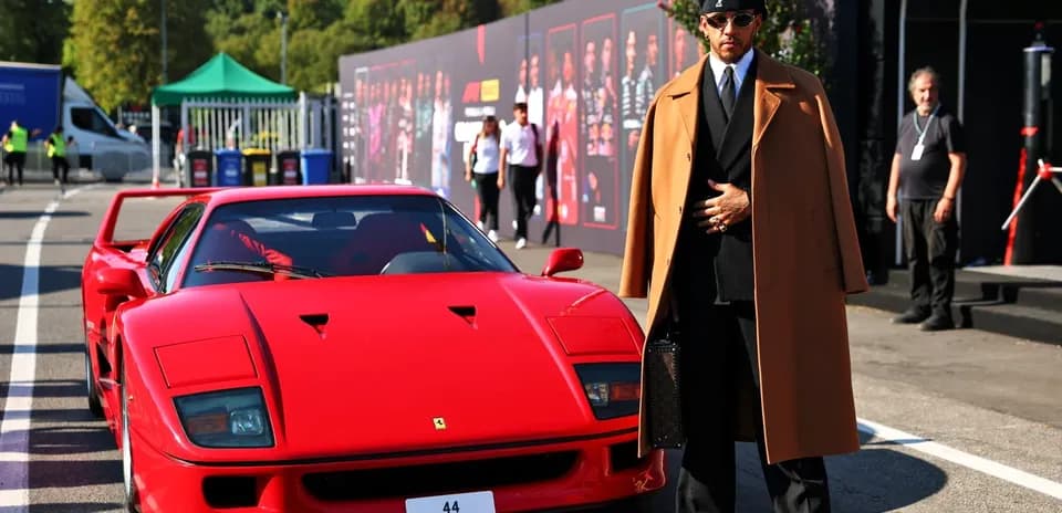 Shirted man in coat beside a red Ferrari