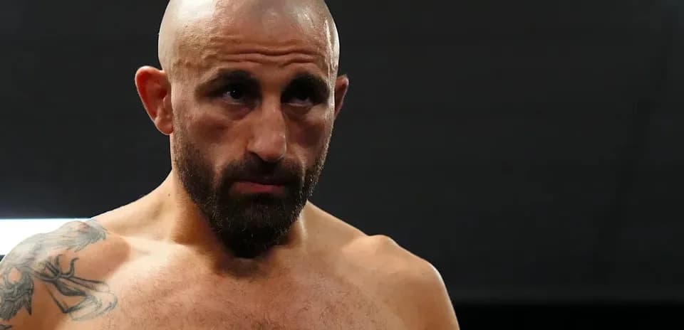 Bald fighter with tattoos in a gym setting
