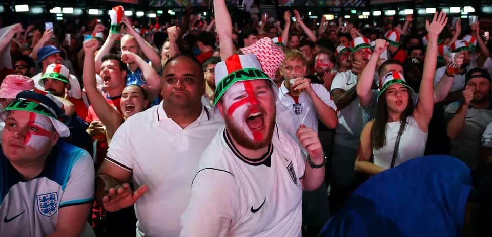 Football fans celebrating in crowded venue with flags