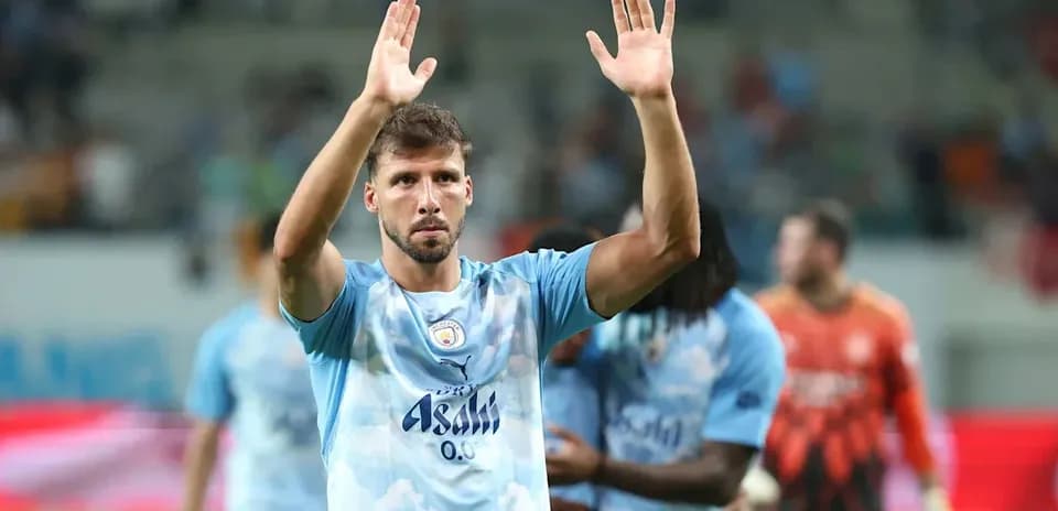 Futbolchi jamoa oldida qo'l silkitmoqda