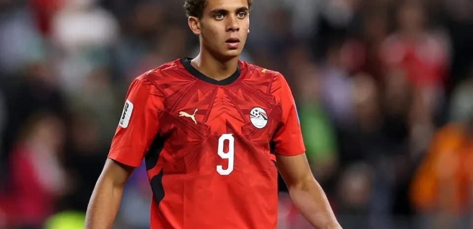 Futbolchi maydonda harakatda, qizil forma kiygan