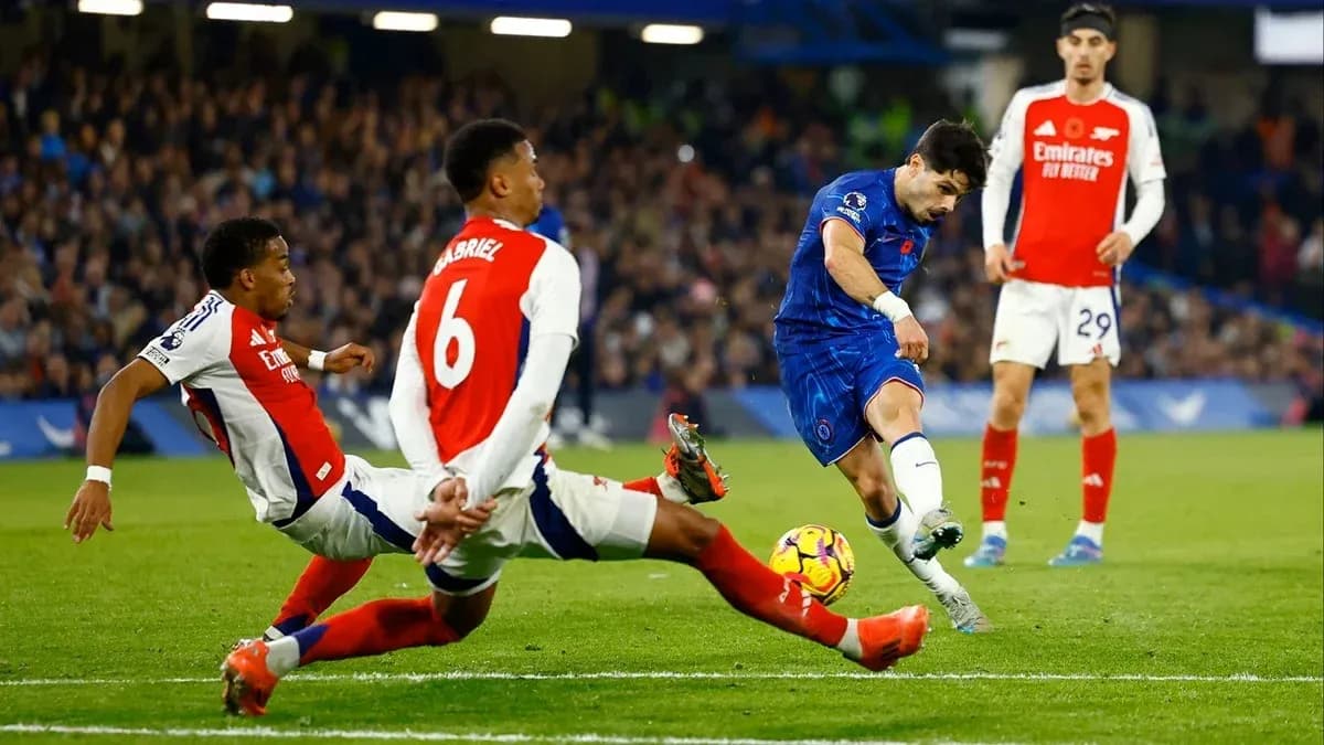 Chelsea player shooting past two Arsenal defenders