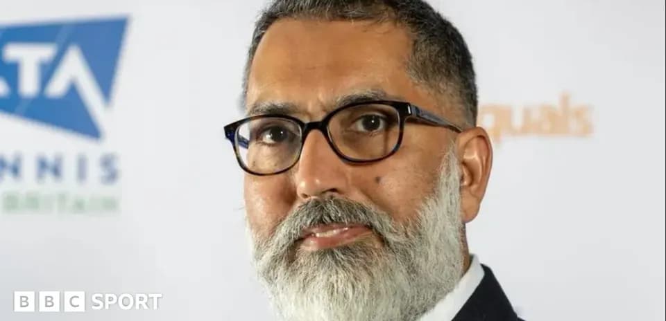 Person with glasses and beard at event backdrop