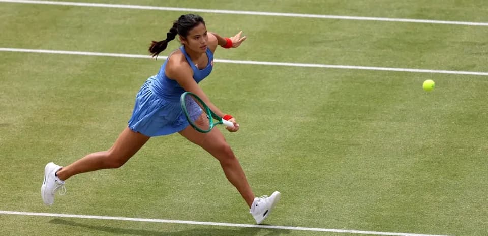 Tennis player returning a shot on grass court