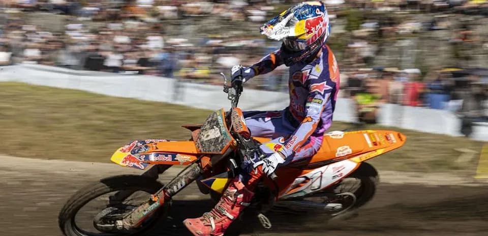 Motocross rider navigating dirt track with spectators