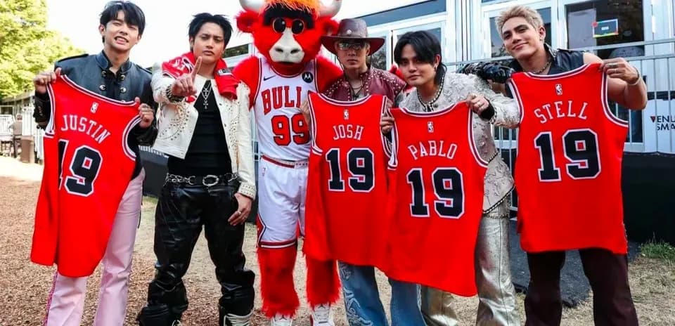 Group holding jerseys with a mascot at event