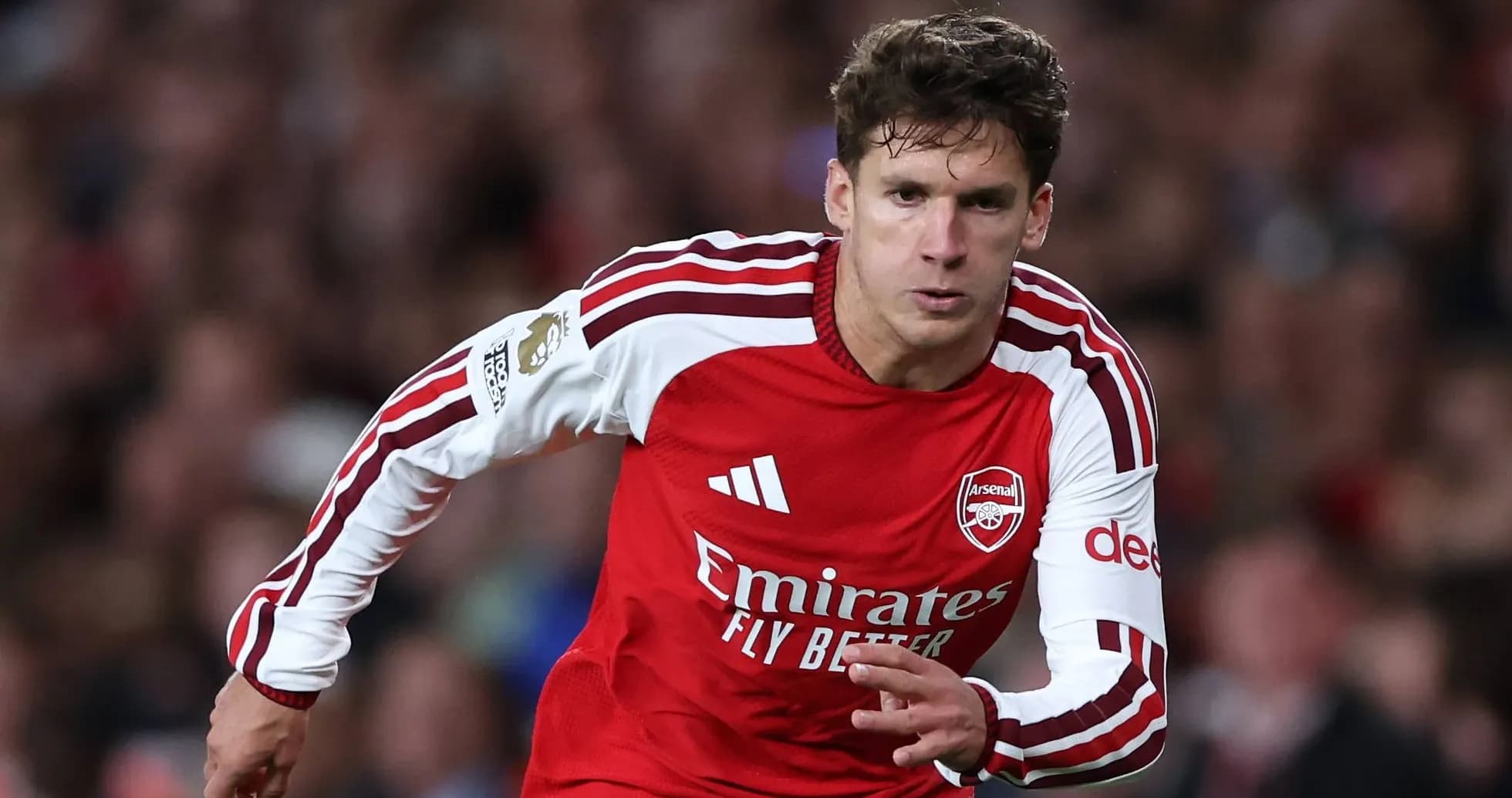Futbolchi Arsenal formasi bilan maydonda yugurmoqda