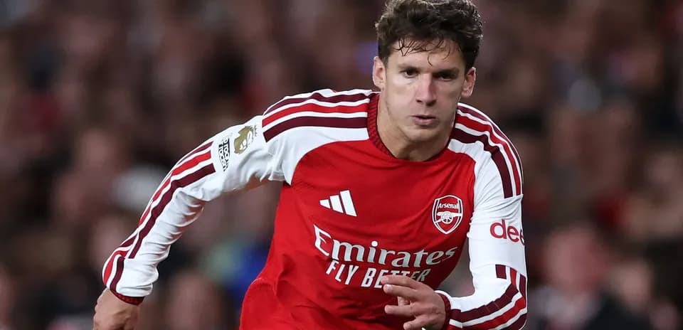 Futbolchi Arsenal formasi bilan maydonda yugurmoqda
