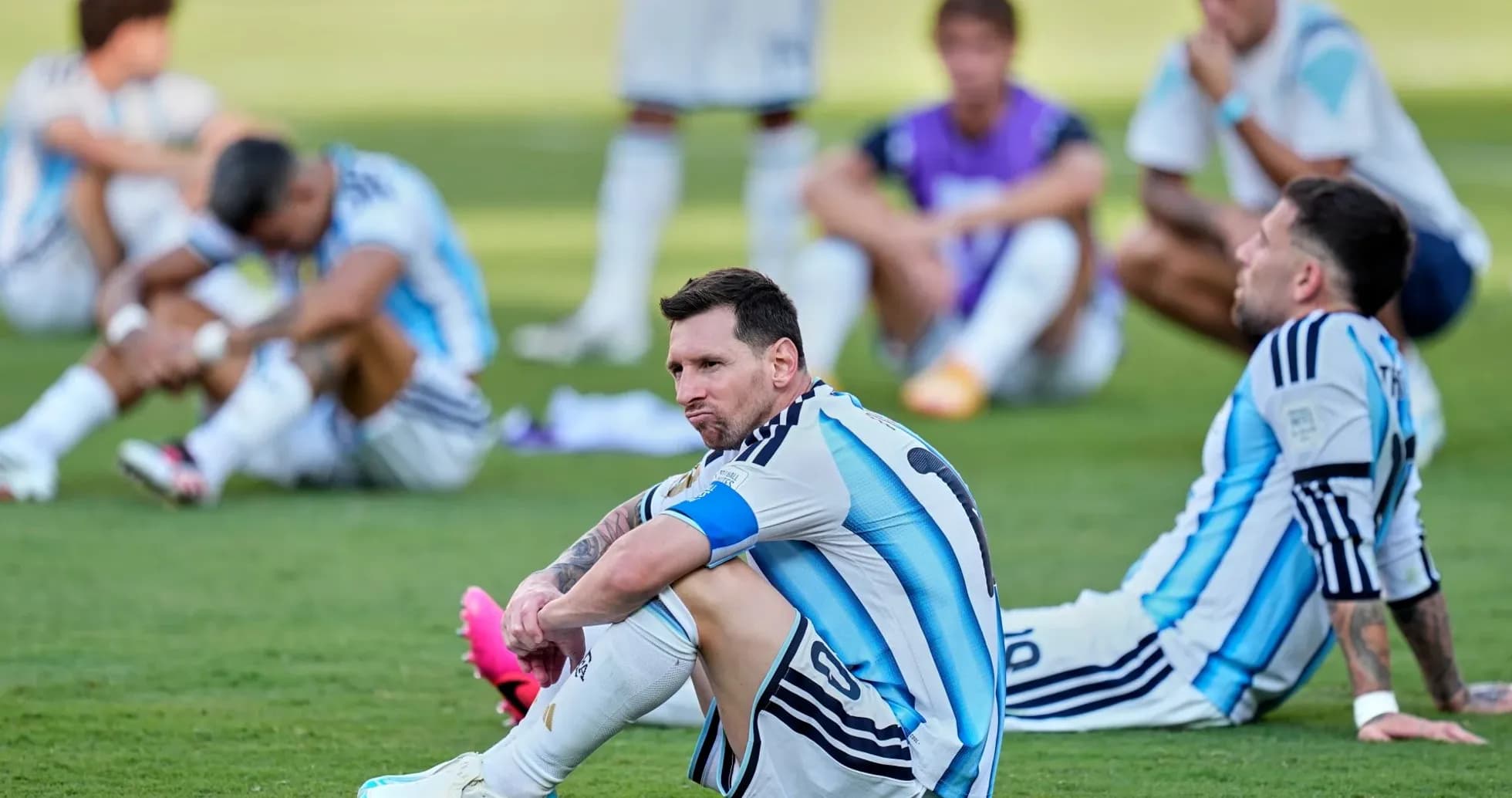 Lionel Messi sitting on the pitch with teammates