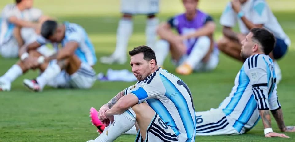 Lionel Messi sitting on the pitch with teammates