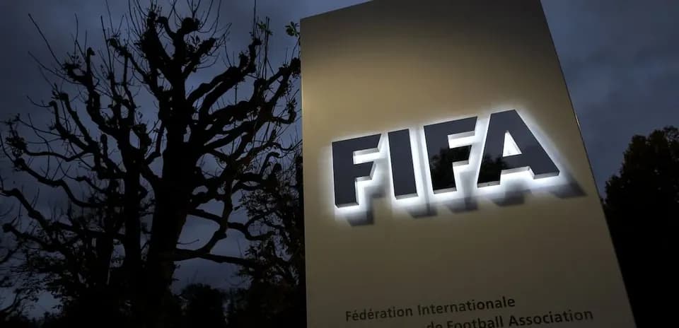 FIFA sign illuminated at night near tree