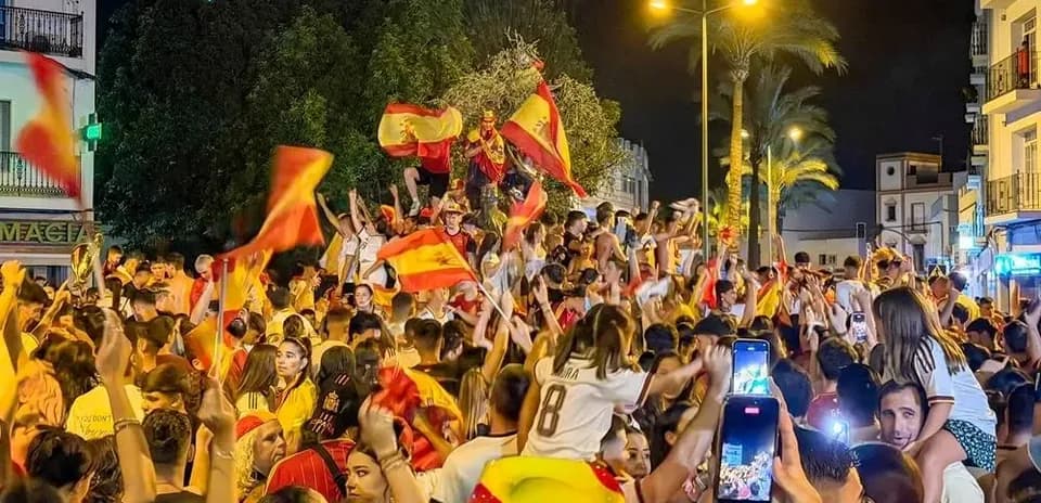 Odamlar Ispaniya bayroqlarini tutib, bayram qilmoqda