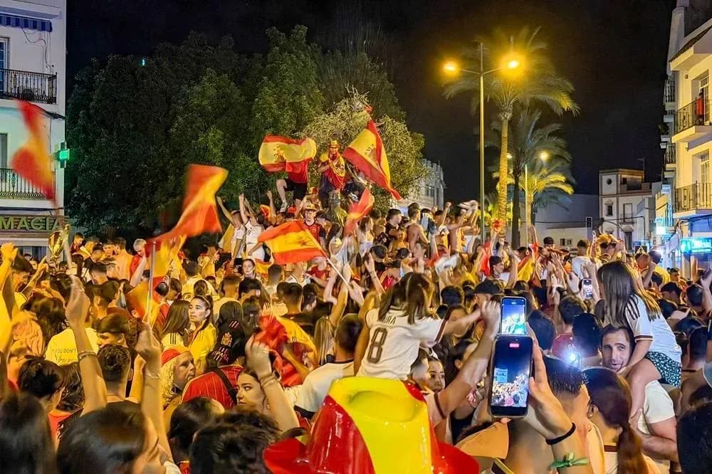 Odamlar Ispaniya bayroqlarini tutib, bayram qilmoqda