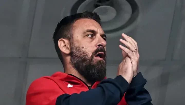 Man applauding in sports venue wearing red jacket