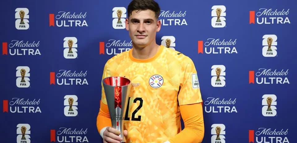 Goalkeeper holding trophy in front of sponsor backdrop