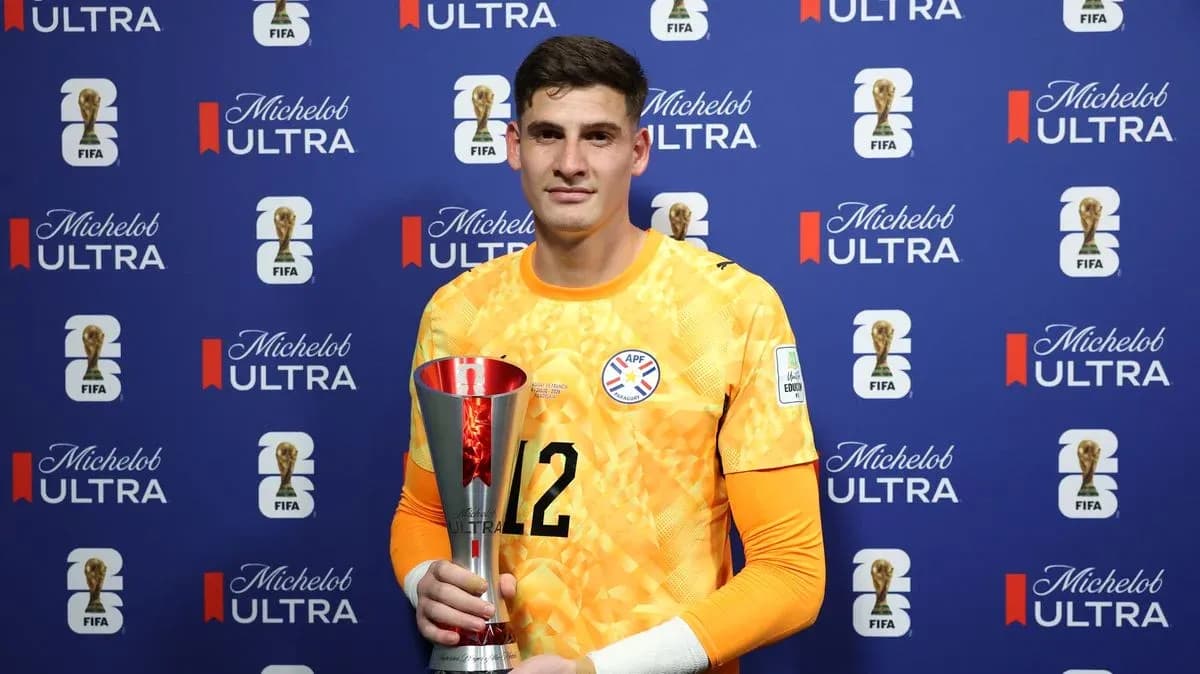 Goalkeeper holding trophy in front of sponsor backdrop