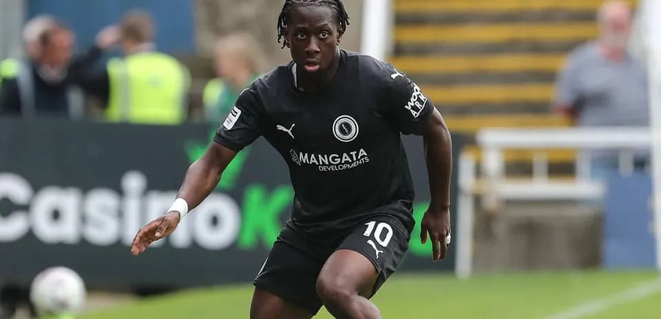 Futbolchi qora formada maydon bo'ylab harakatda