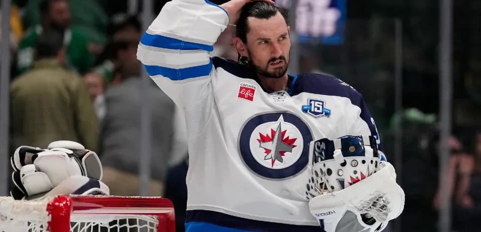 Hockey player in Winnipeg Jets uniform holding helmet