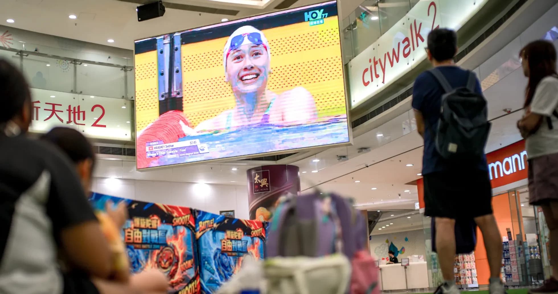 Swimmer celebrating victory on large screen in mall