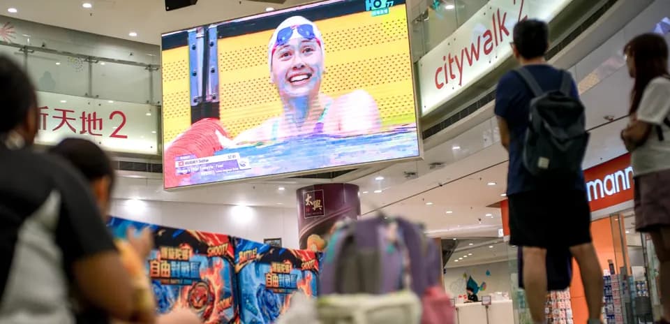 Swimmer celebrating victory on large screen in mall