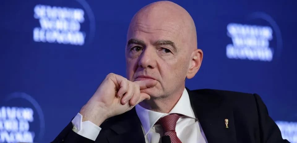 Man in suit speaking at conference with logo backdrop