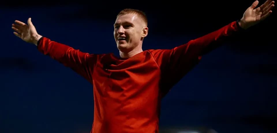 Futbolchi qizil formada qo'llarini keng yoygan