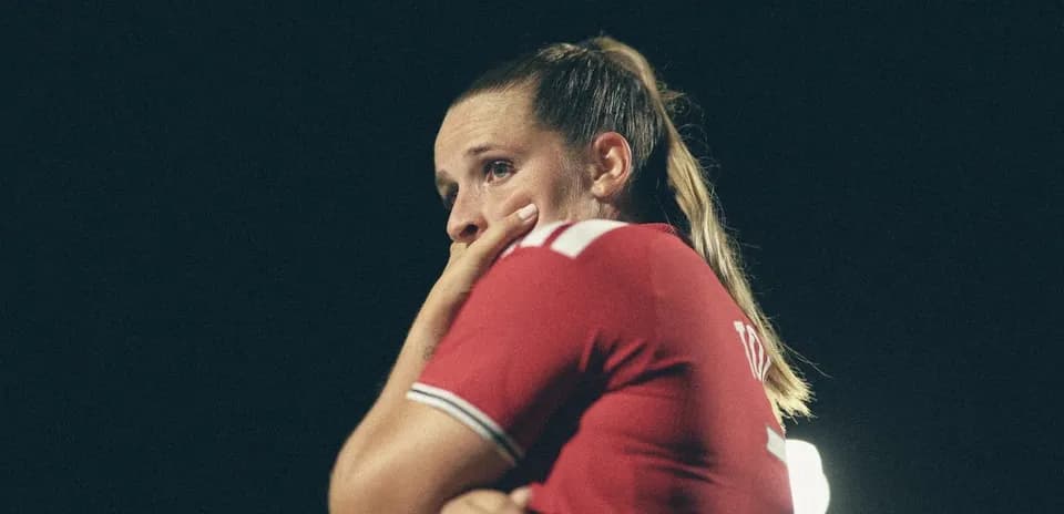 Futbolchi qiz o'yin davomida qo'lini og'zida ushlab turmoqda