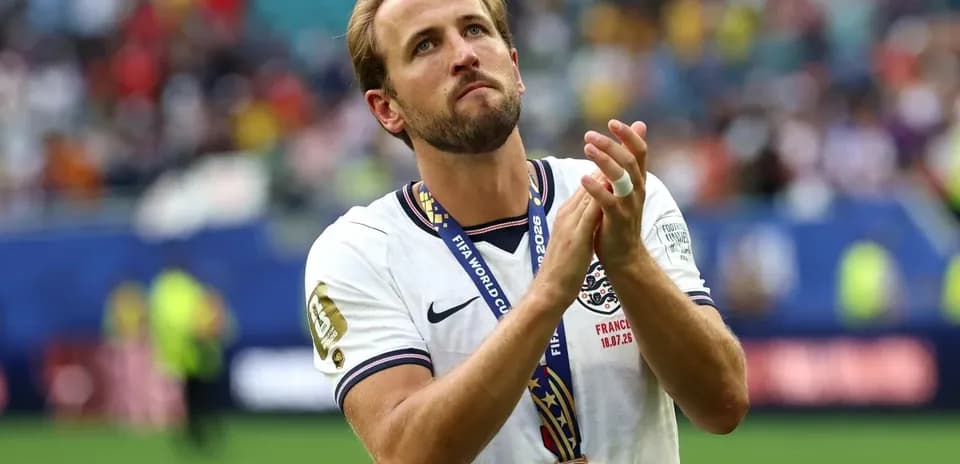Futbolchi medal bilan maydonda qo'llarini ko'tarib turibdi