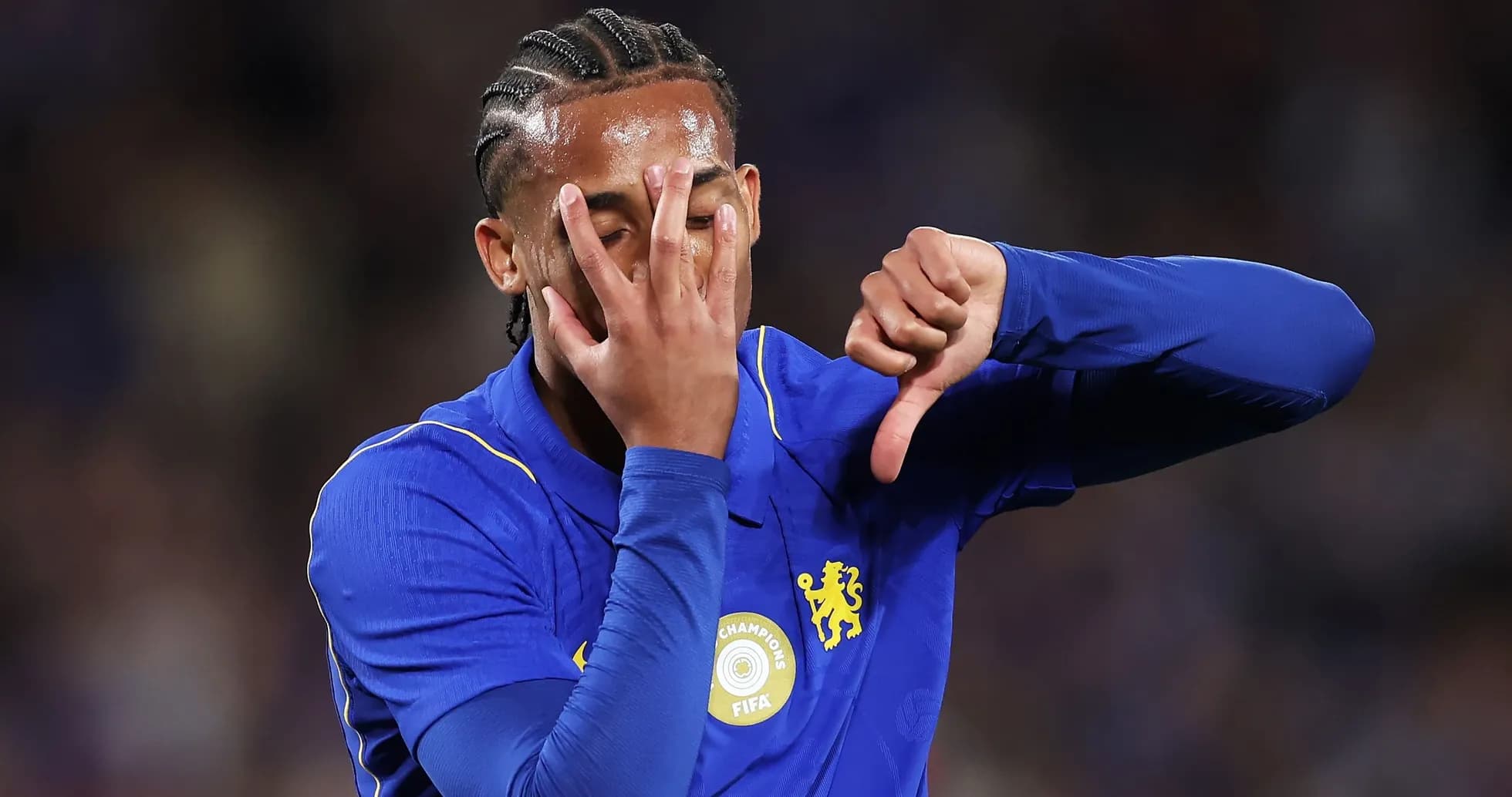 Futbolchi Chelsea formasida, qo'l bilan norozilik bildirmoqda