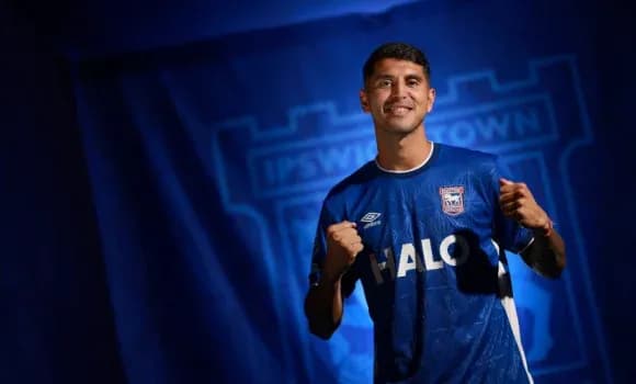 Futbolchi Ipswich Town formasida, qo'llarini ko'tarib turibdi