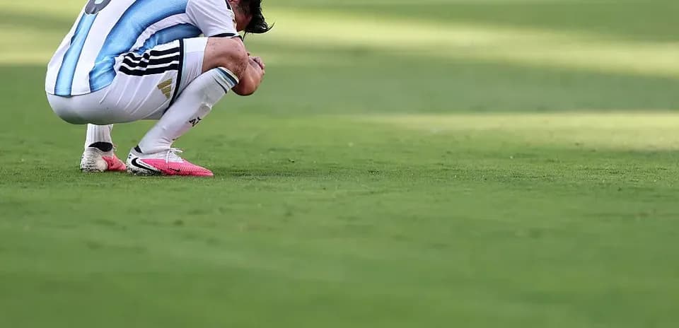 Futbolchi maydonda egilib o'tirgan holatda