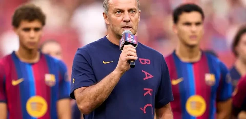 Murabbiy mikrofonda so'zlayapti, futbolchilar orqasida