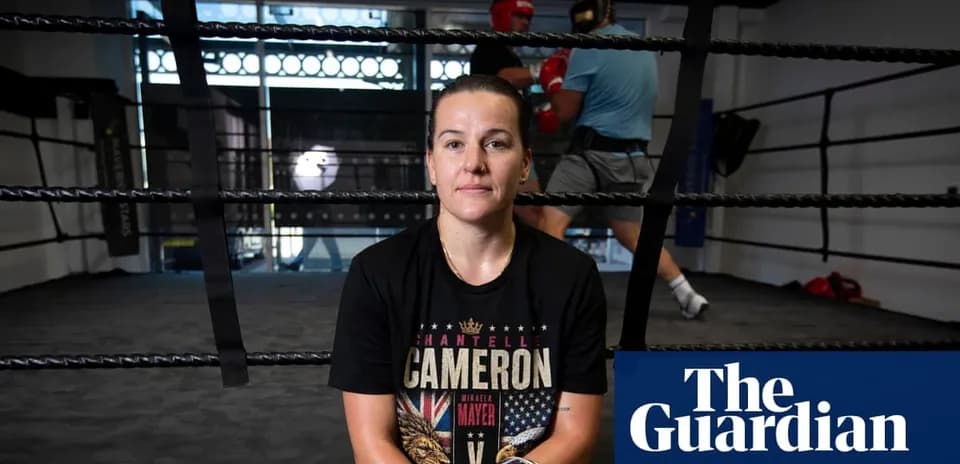 Boxer sitting in ring with training partners in background