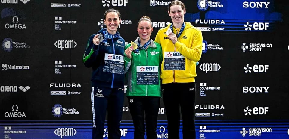 Three swimmers on podium with medals at championship