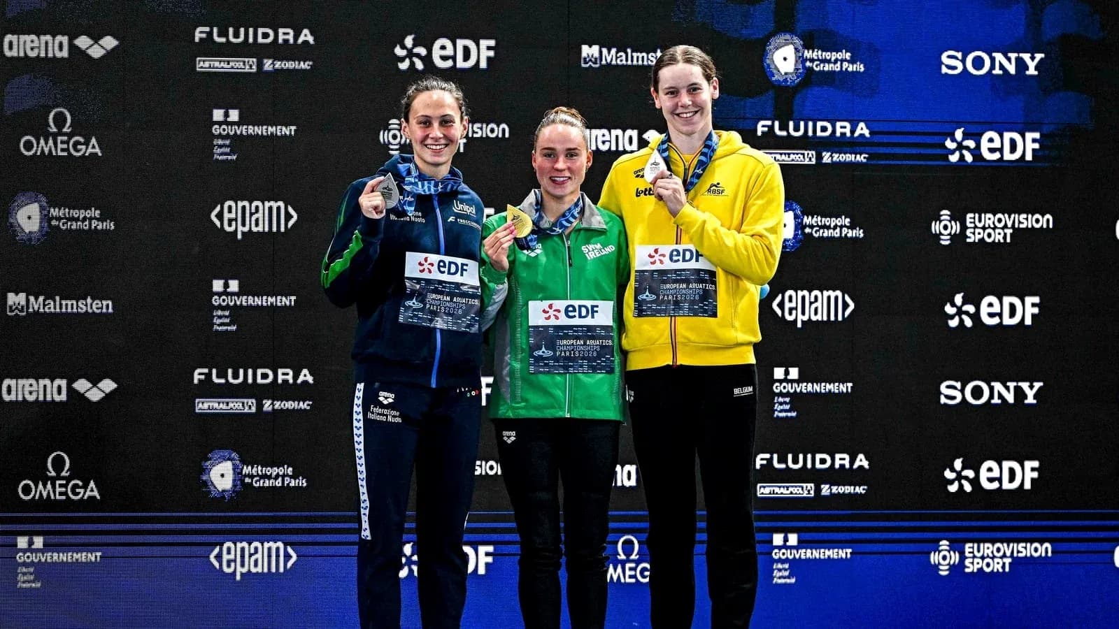 Three swimmers on podium with medals at championship