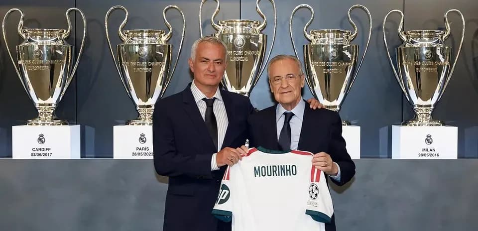 Mourinho holding jersey with trophies in background