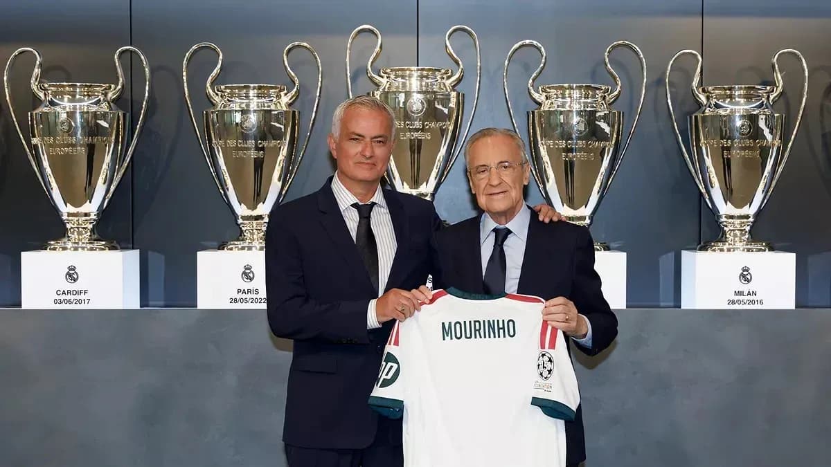 Mourinho holding jersey with trophies in background
