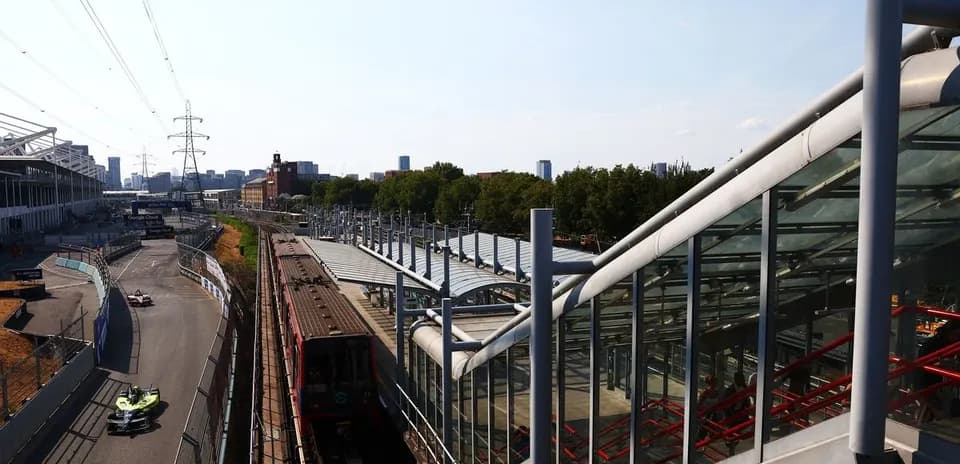 Formula E car racing near train station and city skyline