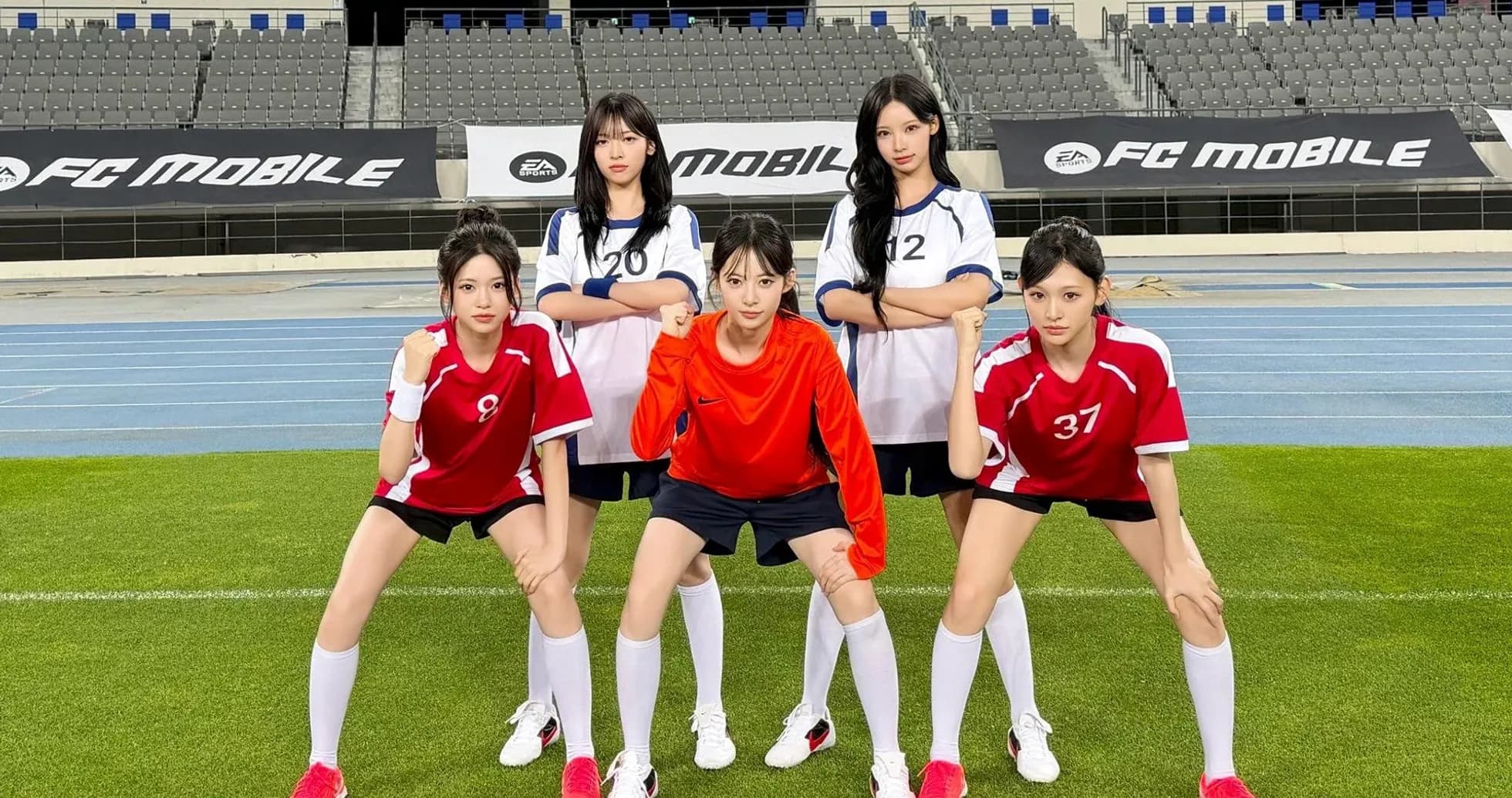 Five players posing in soccer uniforms on field