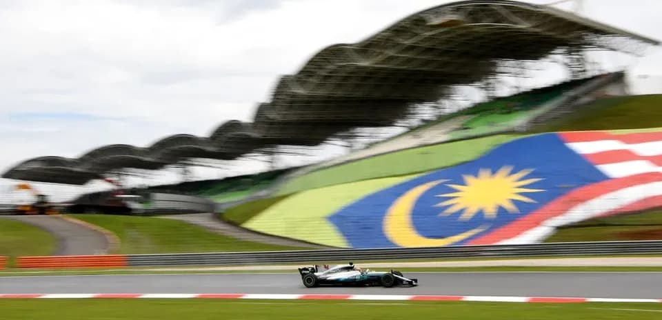 Formula 1 car racing on track with Malaysian flag backdrop