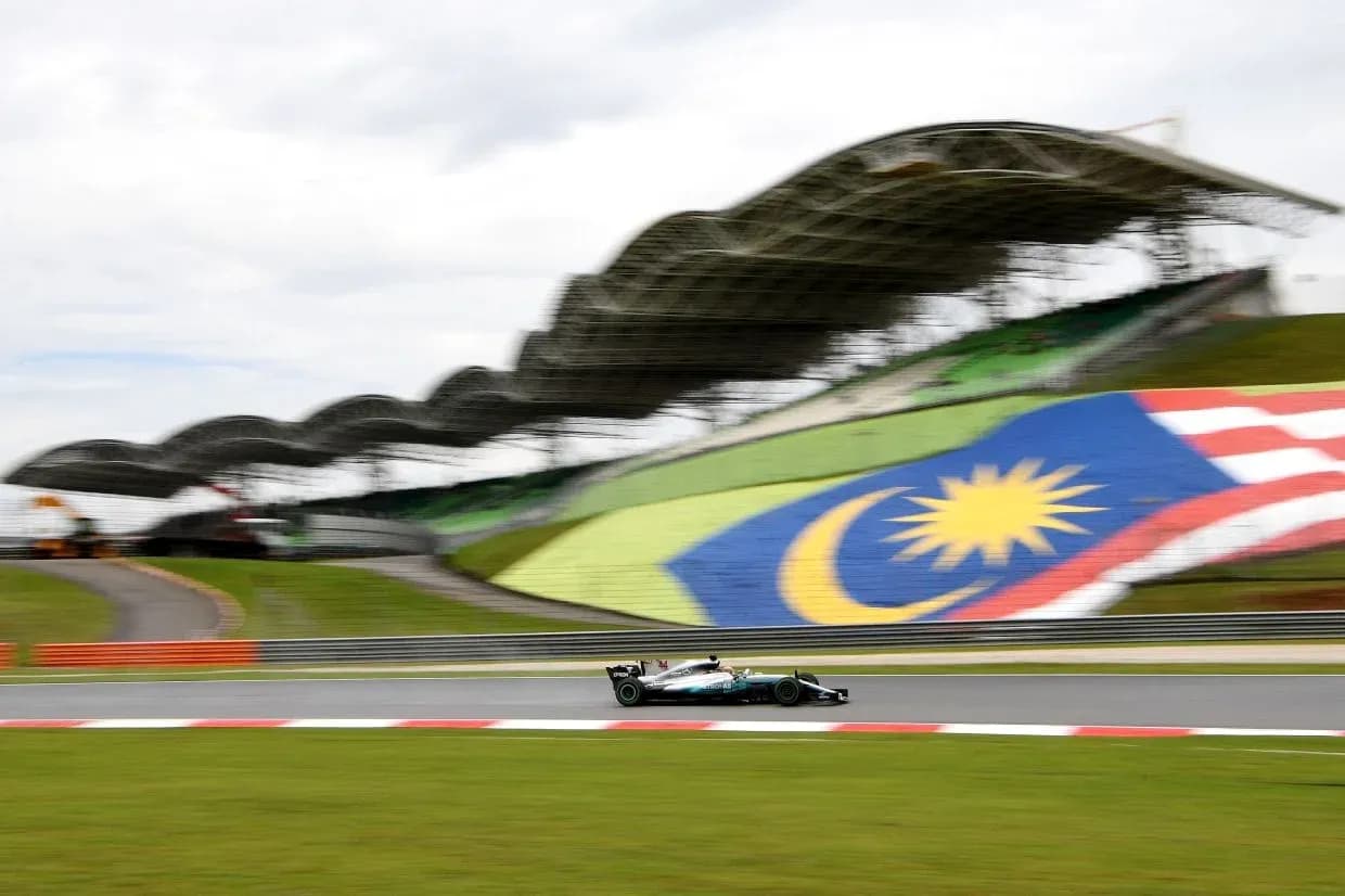 Formula 1 car racing on track with Malaysian flag backdrop