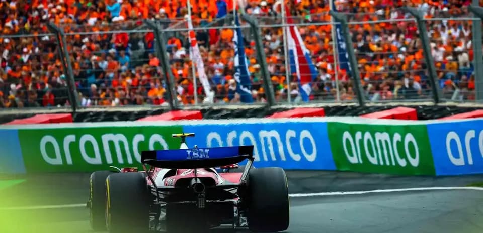 Formula 1 car racing past a cheering crowd