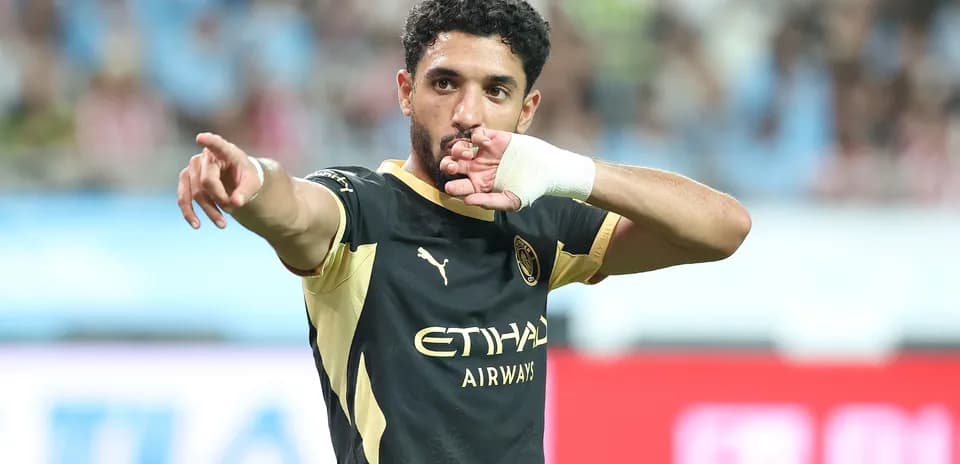 Futbolchi maydonda qo'lini ko'tarib ishora qilmoqda