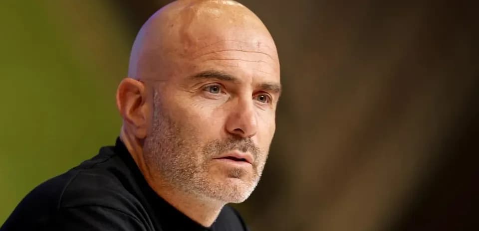 Bald man speaking at a press conference